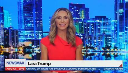 Lara Trump dressed in red, on a blue-tinted Newsmax set with a chyron identifying her